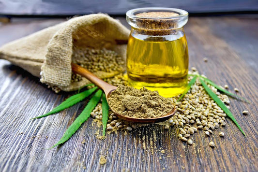 Flour hemp in a wooden spoon, seed in a bag and on the table, oil in a glass jar